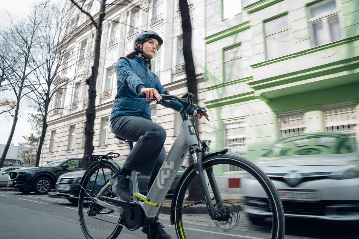 Présentation vélo Husqvana towner avec une femme faisan du vélo en portant un casque